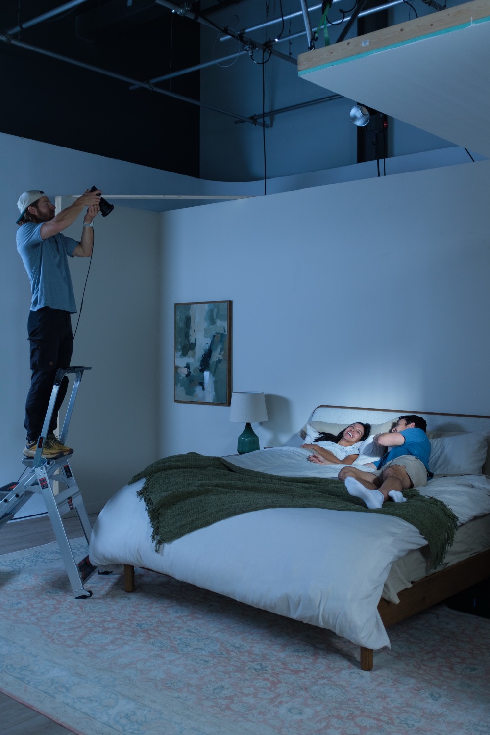 Photographer on a ladder shooting a night scene of a couple on the set.