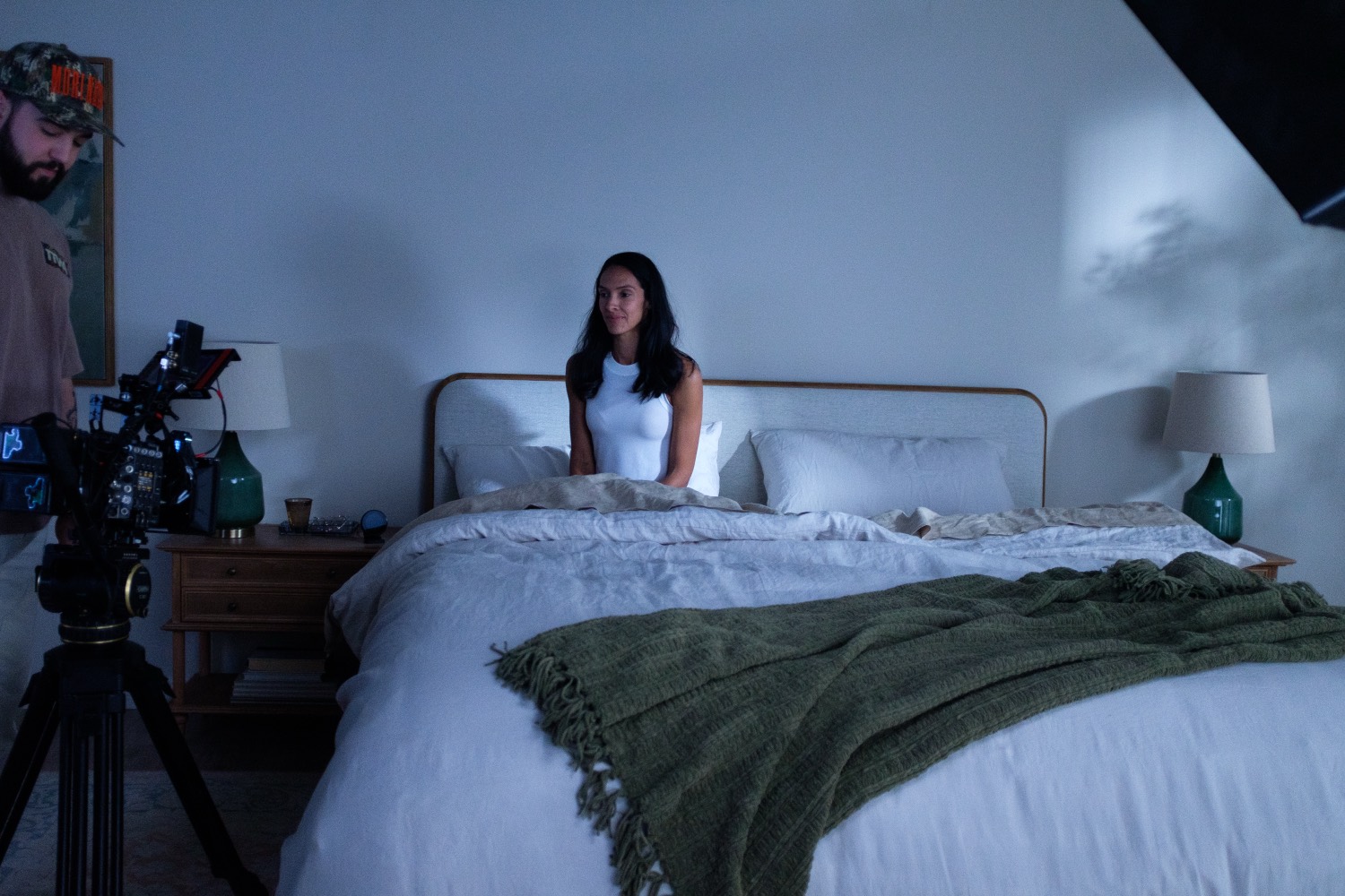 Camera operator framing up talent on the bed.