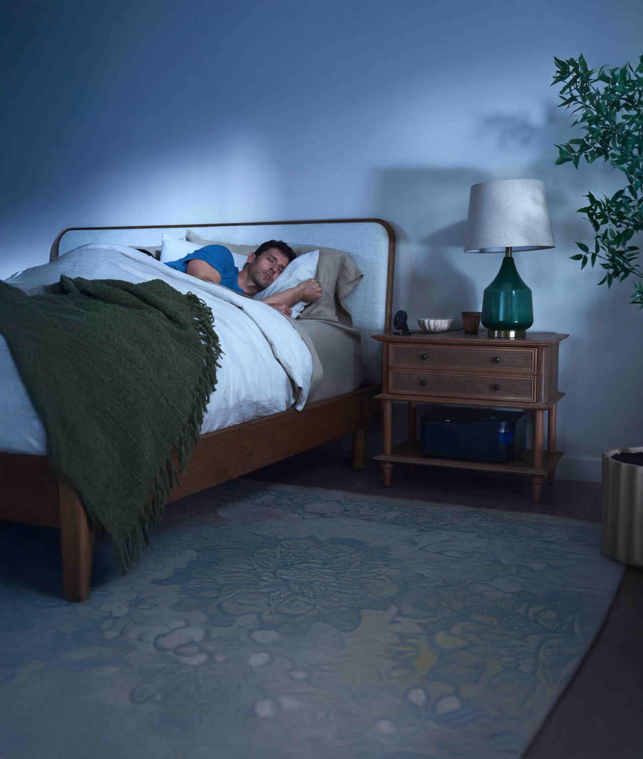 Woman asleep, cool tones, control unit at the foot of the bed.