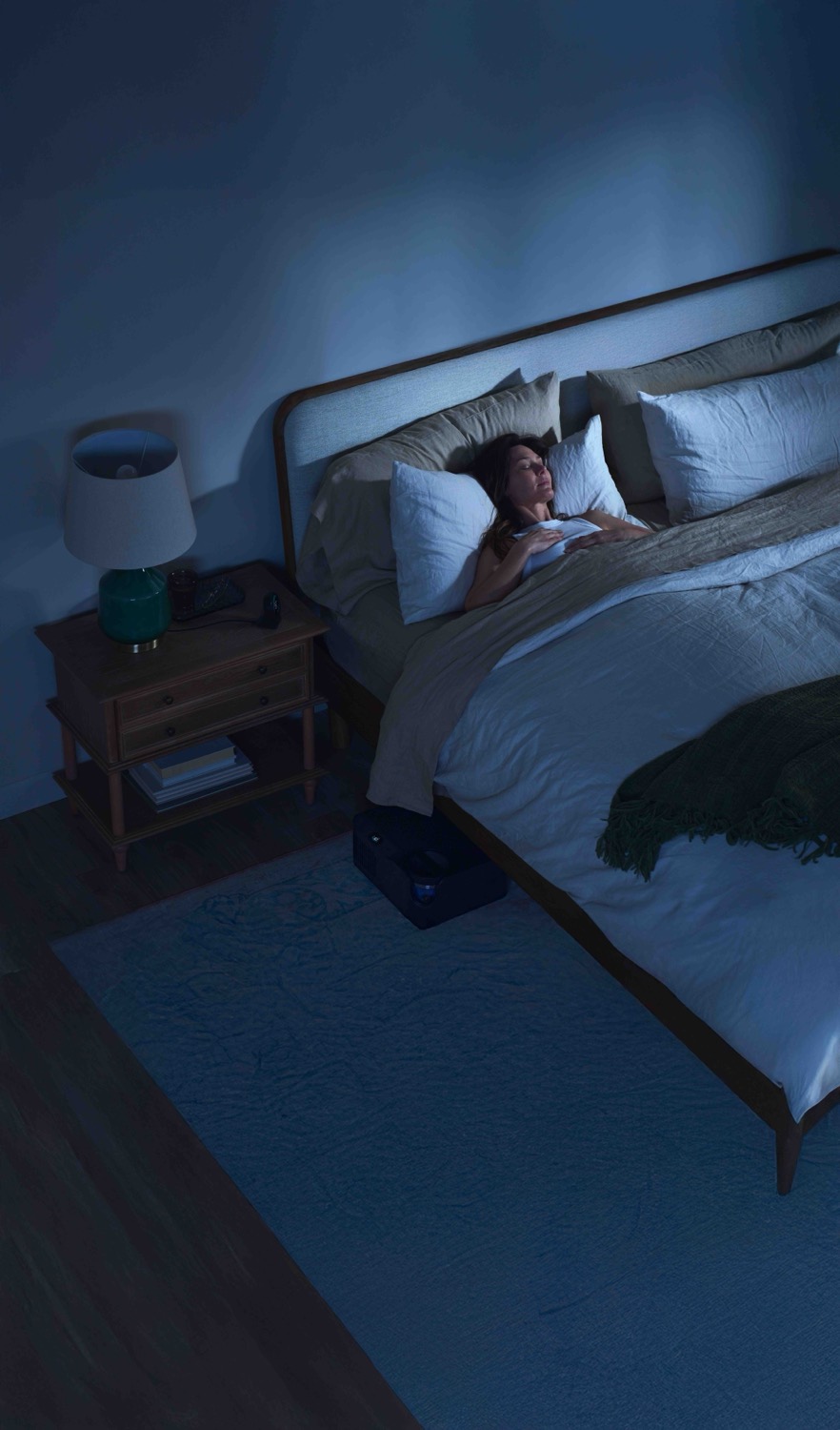 Overhead view of a woman sleeping in cool light.