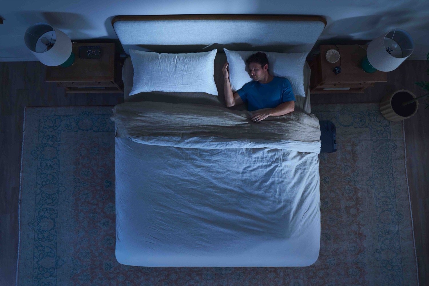 Top-down hero of a man asleep in a styled bedroom set.