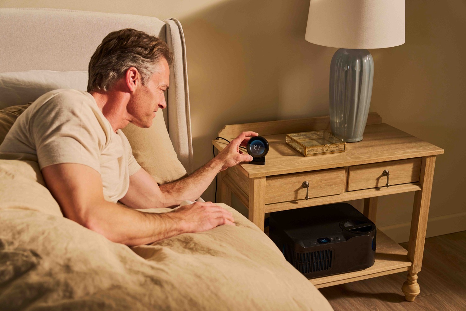 Man reaching for the bedside control in warm light.